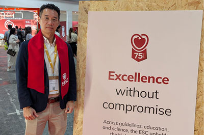 Dr. Joshua Loh standing with a sign with Excellence without Compromise written at the ESC Congress 2025